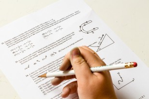 main d'étudiant tenant un crayon pour répondre à un exercice de maths