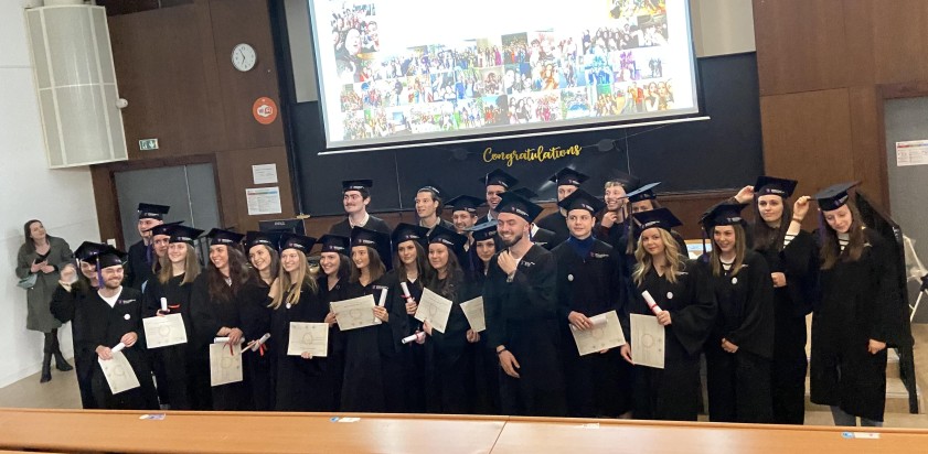 étudiants en toges noires avec leur diplôme debout dans l'amphi